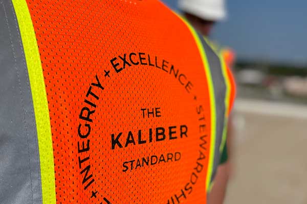 orange safety vest with The Kaliber Standard logo on it