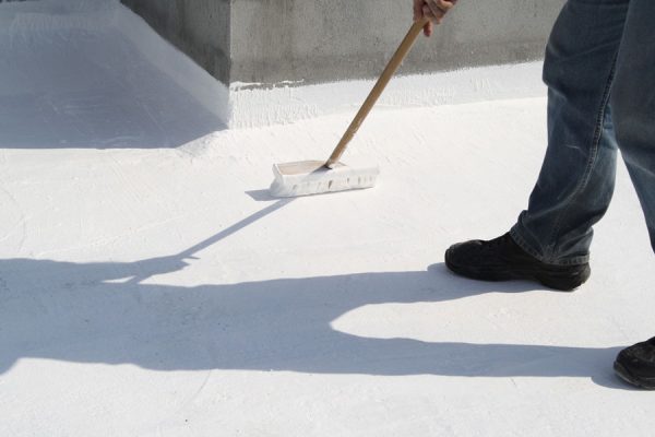 person applying roof coating to commercial roof